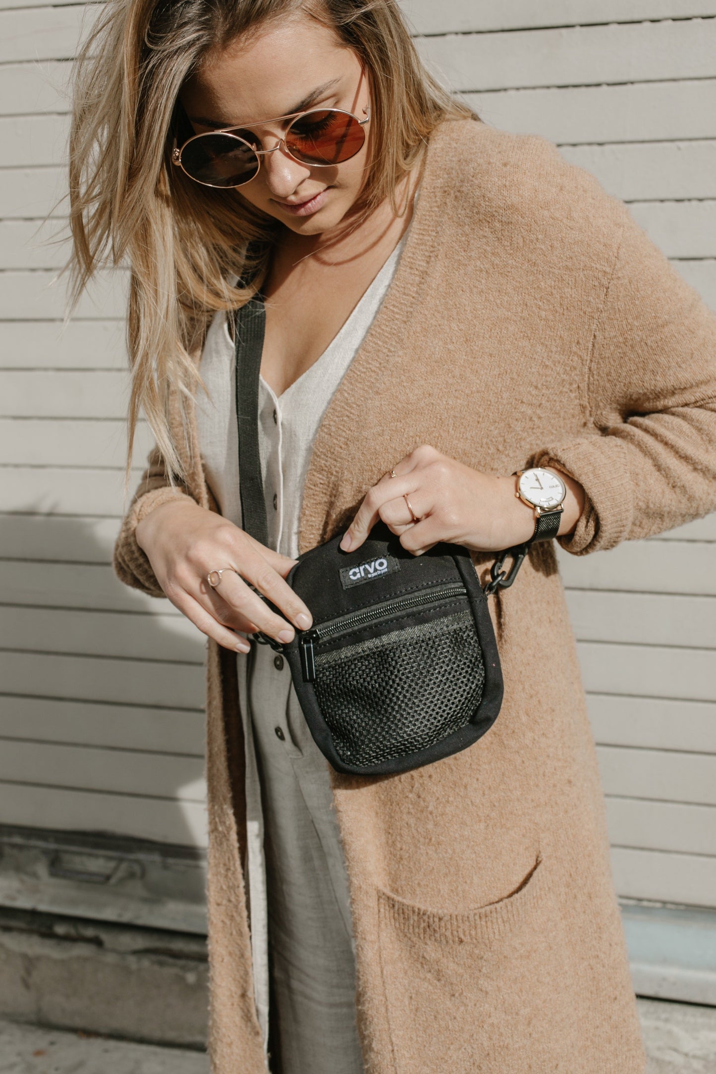 woman wearing a brown sweater looking into an Arvo Fanny canvas crossbody bags for women in a color named pepper which is black